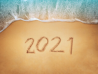 Happy New Year 2021, lettering on the beach with wave and blue sea. Numbers 2021 year on the sea shore, New Years concept.