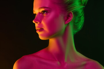 Secretly. Portrait of female fashion model in neon light on dark studio background. Beautiful caucasian woman with trendy make-up and well-kept skin. Vivid style, beauty concept. Close up. Copyspace