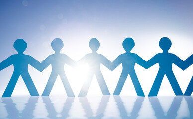 Papierm&auml;nnchen als Menschenkette vor wei&szlig;em hintergrund