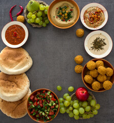 Food frame or border. Colorful authentic meals top view photo: plate of hummus, falafels, salad, pita bread and tahini sauce. 