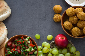 Food frame or border. Colorful authentic meals top view photo: plate of hummus, falafels, salad, pita bread and tahini sauce. 
