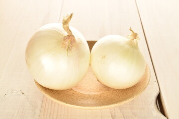 Ripe white organic onions, close-up, on a white wooden table.