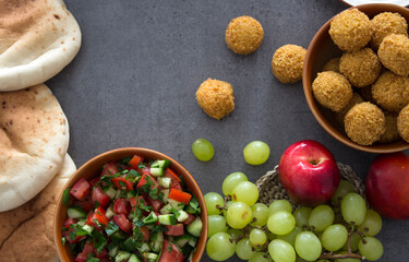 Food frame or border. Colorful authentic meals top view photo: plate of hummus, falafels, salad, pita bread and tahini sauce. 