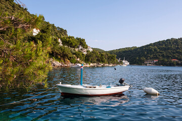 The pretty ferry port of Ubli in the bay of Velji Lago on Lastovo, Dubrovnik-Neretva, Croatia, with a little fishing boat at anchor in the foreground