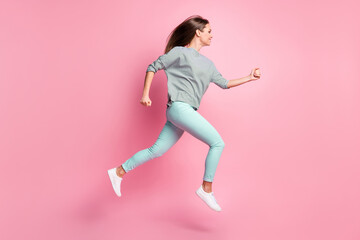 Fototapeta na wymiar Full size profile photo of sweet long hair girl jumping run hands fists wear shirt blue pants white sneakers isolated on pink background