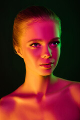 Inspired. Portrait of female fashion model in neon light on dark studio background. Beautiful caucasian woman with trendy make-up and well-kept skin. Vivid style, beauty concept. Close up. Copyspace