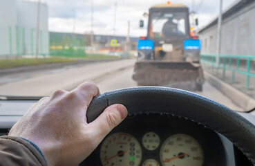driver hand on the steering wheel of a car that is traveling on the roadway in a jam, makes a...