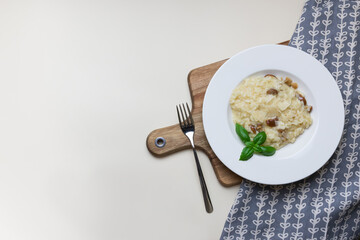 Vegetarian gourmet mushroom risotto on a white plate, yellow background, view from above. Risotto is a northern Italian rice dish cooked with broth until it reaches a creamy consistency.