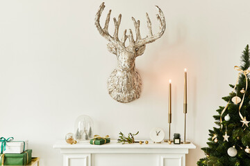Christmas composition on the white chimney at the living room interior with beautiful decoration. Christmas tree and wreath, candles, stars, light. Copy space.  Template.