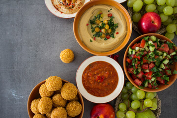   Authentic food of Middle East. Plate of hummus, falafels, pita bread, harissa sauce, tahini, fresh salad and fruits on wooden table. Traditional meals of Israel top view photo. Beautiful food pictur