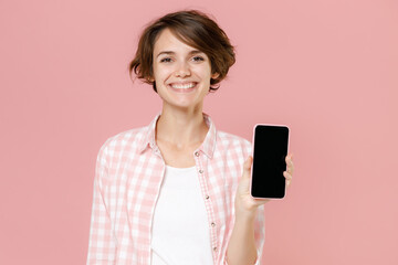 Smiling young brunette woman wearing casual basic checkered shirt standing hold mobile cell phone...