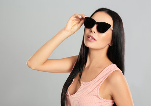 Beautiful woman wearing sunglasses on grey background