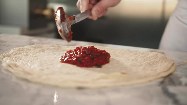 Italian chef making margaritta pizza with tomato sause and mozzarella, traditional food in italy, high kitchen gastrobar restaurant, street food delivery.