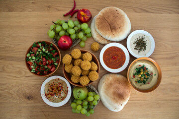 Traditional food of Israel on dark grey background with copy space. Colorful authentic meals top view photo: plate of hummus, falafels, salad, pita bread and tahini sauce. 