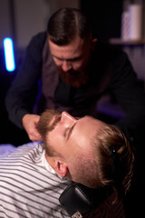 caucasian hipster client man visiting in barber shop shaving beard by professional hairdresser, stylish and and modern beard in salon