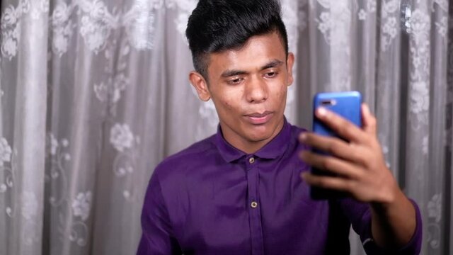 Smiling young man using his phone to make a video call