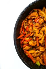 Chinese cuisine. Chicken in sweet and sour sauce with pepper in a frying pan on a white background. The kitchen of the world.