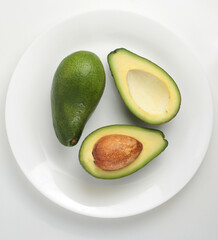 Group of fresh avocados on a plate on a white background. Top view.