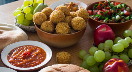 Traditional food of Israel on dark grey background with copy space. Colorful authentic meals top view photo: plate of hummus, falafels, salad, pita bread and tahini sauce. 