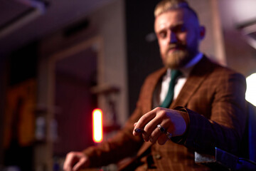 close-up photo of cigar in hand on confident rich guy sitting in dark room smoking alone