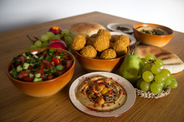 Traditional food of Israel on dark grey background with copy space. Colorful authentic meals top view photo: plate of hummus, falafels, salad, pita bread and tahini sauce. 