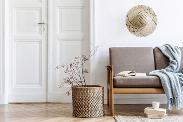 Stylish and cozy interior of living room with design brown sofa and elegant rattan accessories....
