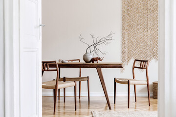 Stylish beige interior of dining room with design wooden oak table and chairs, vase with flowers,...