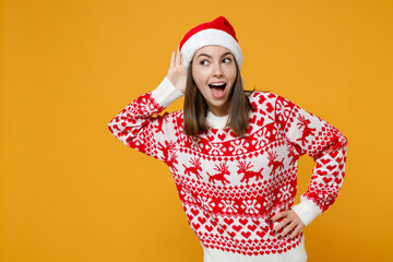Curious young Santa woman 20s in red sweater Christmas hat try to hear you overhear listening...
