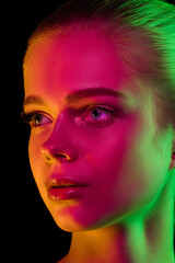 Skin glow. Portrait of female fashion model in neon light on dark studio background. Beautiful caucasian woman with trendy make-up and well-kept skin. Vivid style, beauty concept. Close up.