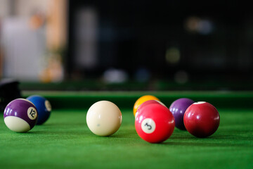 Man's hand and Cue arm playing snooker game or preparing aiming to shoot pool balls on a green billiard table. Colorful snooker balls on green frieze.