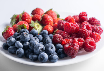 Fresh delicious berries Strawberries, blueberries and raspberries close-up in a white plate