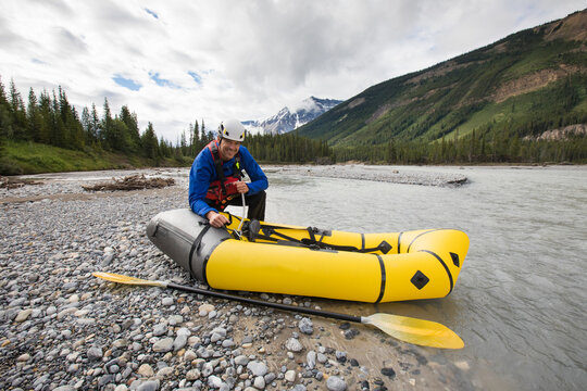 Paddler inflates yellow packraft next to North Saskatchewan River.