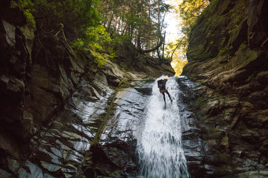Low angle view of man rappelling down waterfall in Cypress Canyon.