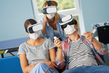 Fototapeta premium Couple of students wearing masks playing video games in the campus