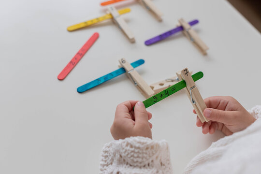 Child solves math examples with wooden sticks , didactic materials , Diy, home education. Mathematics for preschooler.
