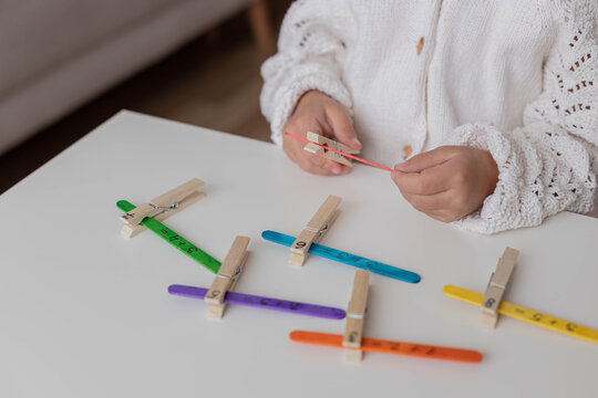 Child solves math examples with wooden sticks , didactic materials , Diy, home education. Mathematics for preschooler.