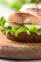 Sandwich with salted herring, rye bread, onions, and lettuce close-up. Scandinavian food.