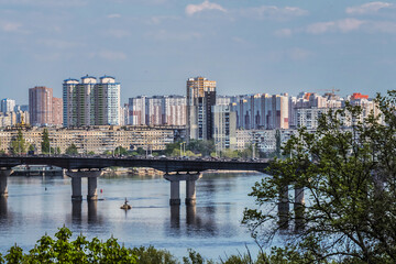 Fototapeta premium View of Dnieper River with Paton Bridge and architecture of Left Bank of Dnieper in Kyiv. Kyiv, Ukraine.