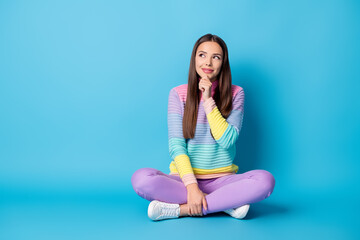 Portrait of smart cheery girl sitting lotus position crossed legs thinking copy space isolated bright blue color background