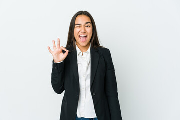 Young asian bussines woman isolated on white background winks an eye and holds an okay gesture with hand.