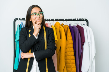 Young asian designer woman isolated on white background looking sideways with doubtful and skeptical expression.