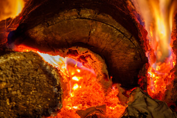 Close up of logs burning in a wood stove with glowing red coals
