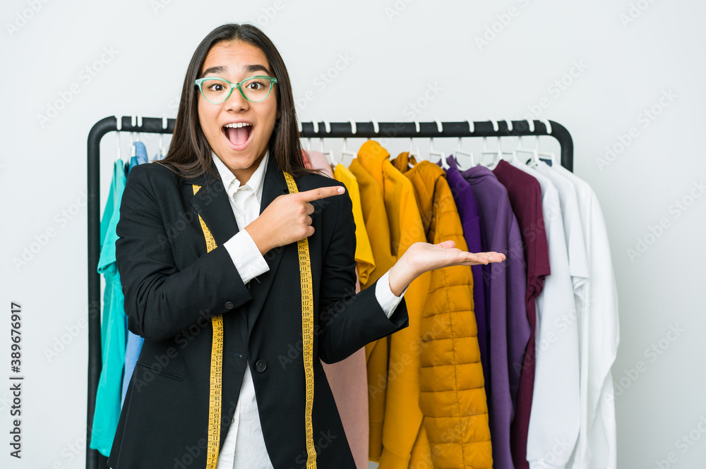 Wall mural Young asian designer woman isolated on white background excited holding a copy space on palm.