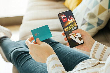Stock photo of a woman going to play online casino and holding a credit card to pay. Online...