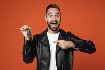 Shocked amazed young bearded man 20s in basic white t-shirt, black leather jacket standing pointing...
