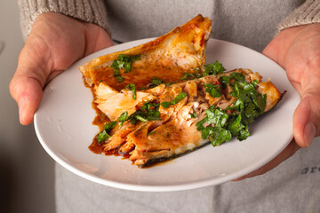 baked salmon on a plate in male hands close-up
