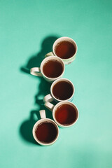 Different mugs of hot drinks - tea, coffee on a turquoise background top view vertical	