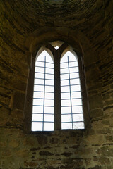 An old castle window seen from the inside of a turret with old arches and a narrow frame. Stone window with metal work.
