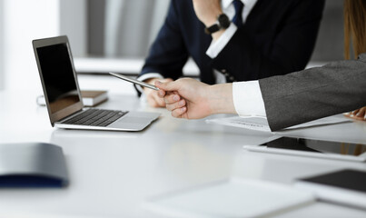 Unknown businessmen and woman sitting, working and discussing questions at meeting in modern office, close-up