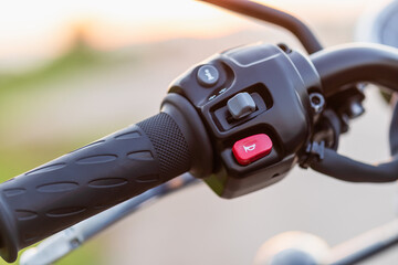 Red horn switch. Left handle bar with hand clutch of motorcycle. Motorcycle maintenance concept outdoor shooting with sunset effect